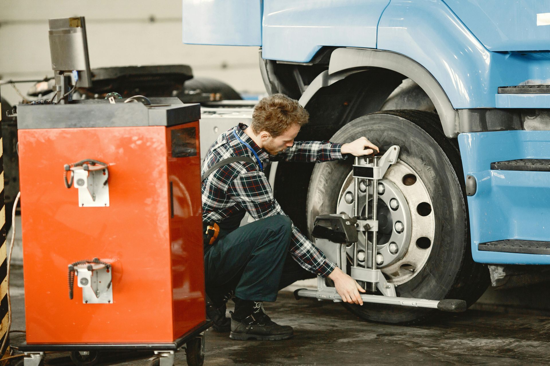 A man is adjusting a tire on a truck in a garage.