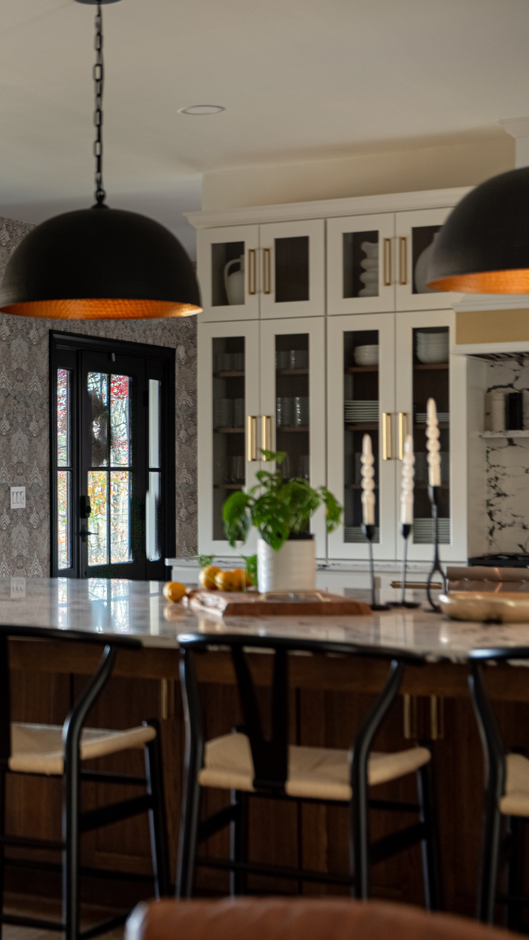 Modern kitchen with black pendant lights, white cabinets, bar stools, and a dark island countertop