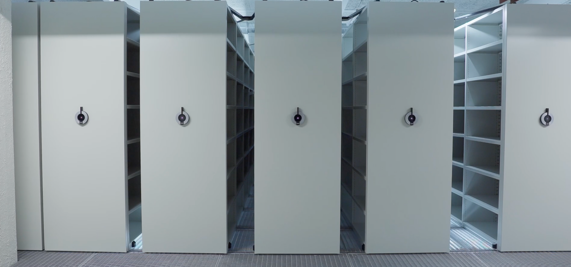 Rows of tall white server cabinets in a data center, with one aisle open between racks.
