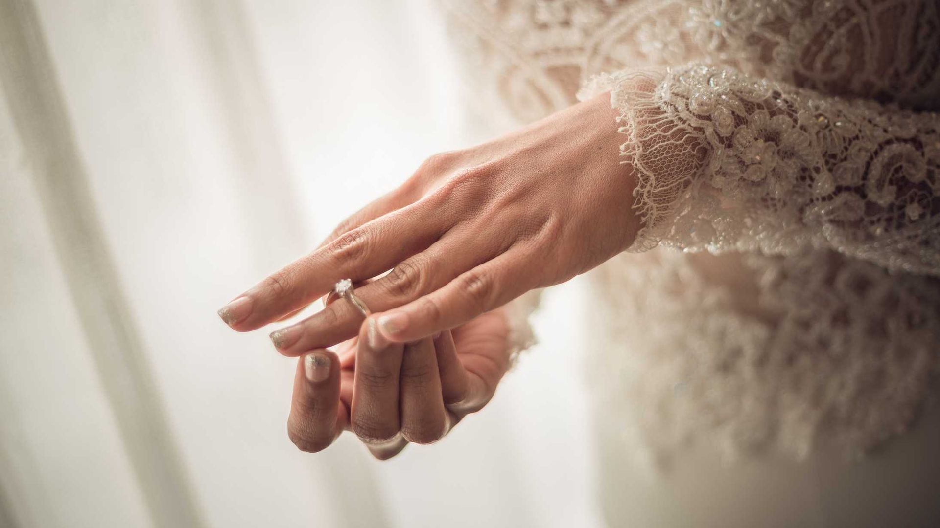 A close up of a woman 's hand with a wedding ring on it.