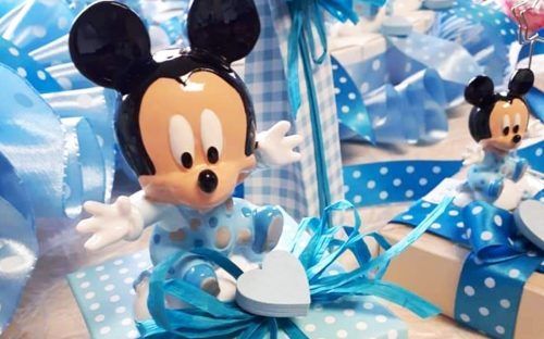 Una statuetta di Topolino è seduta in cima a una scatola regalo.