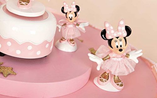Due statuette di Minnie sono sedute in cima a una torta rosa.