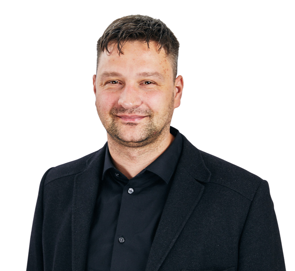 A man wearing a black jacket and a black shirt is smiling for the camera.