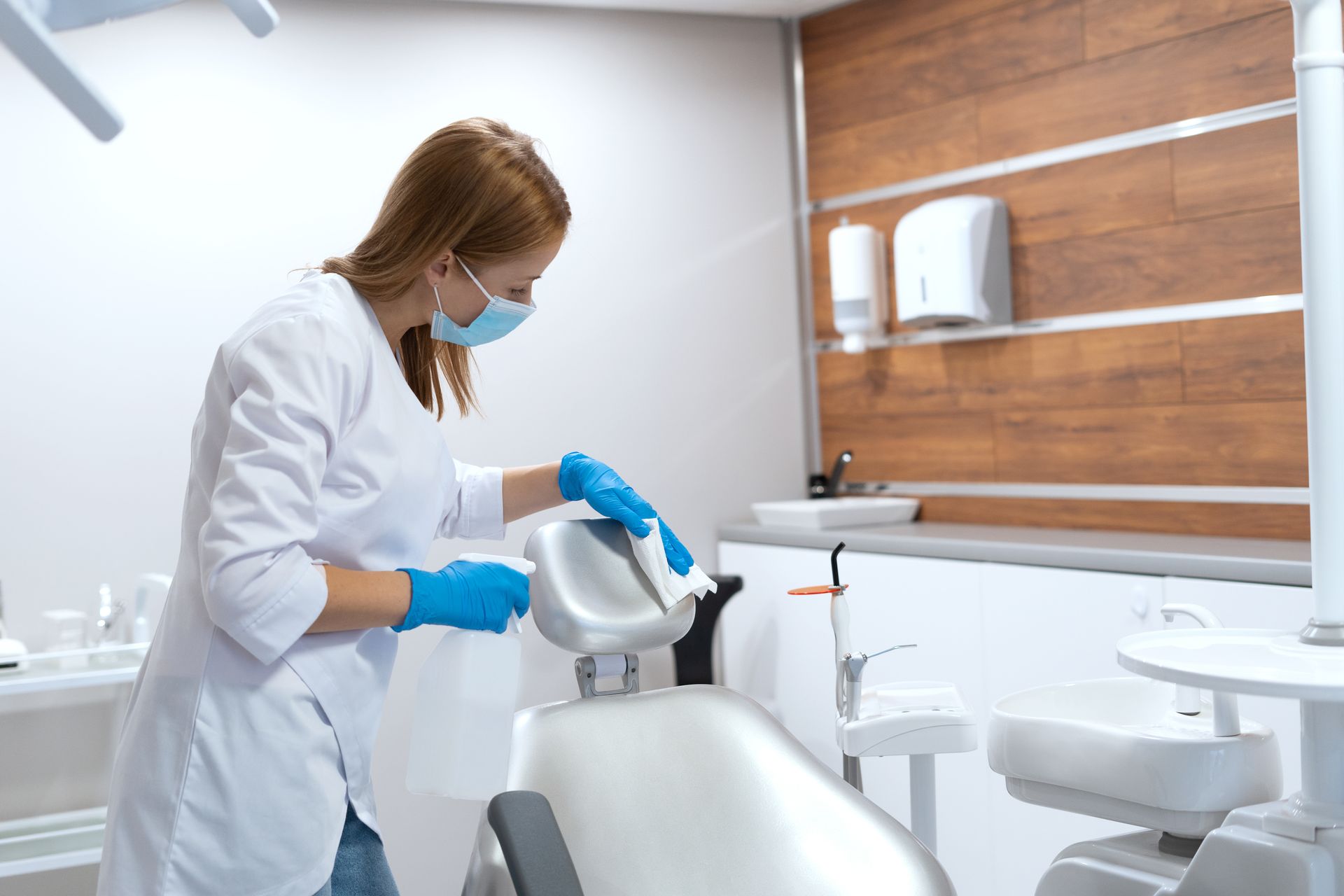 A female dentist is cleaning a dental chair in a dental office.