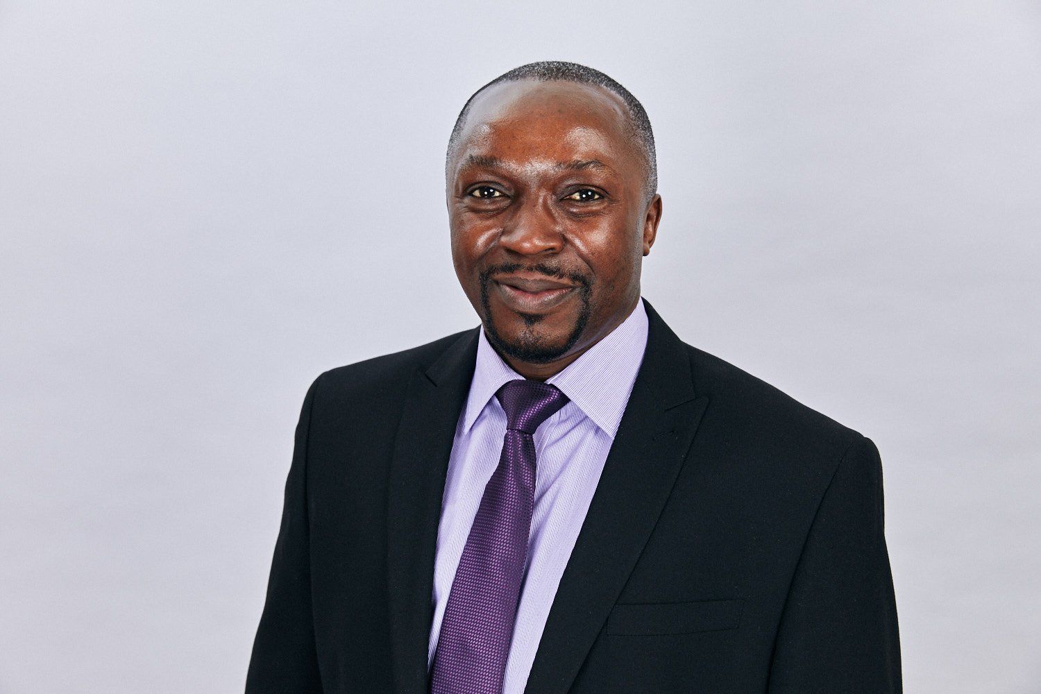 A man in a suit and tie is smiling for the camera.