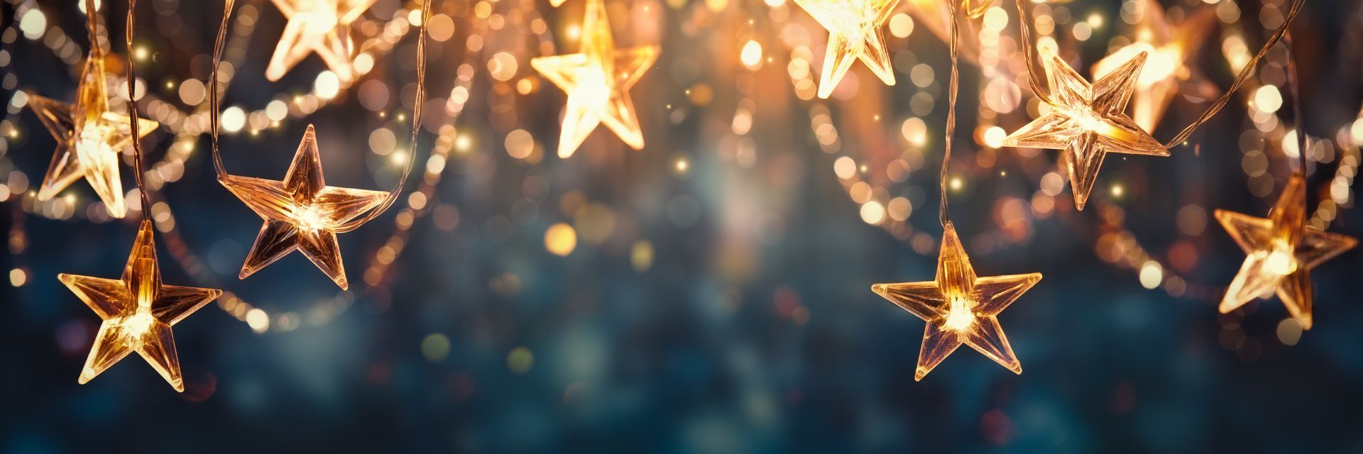 A bunch of gold stars hanging from a string on a dark background.