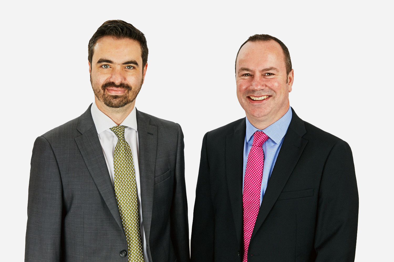 Two men in suits and ties are standing next to each other and smiling.