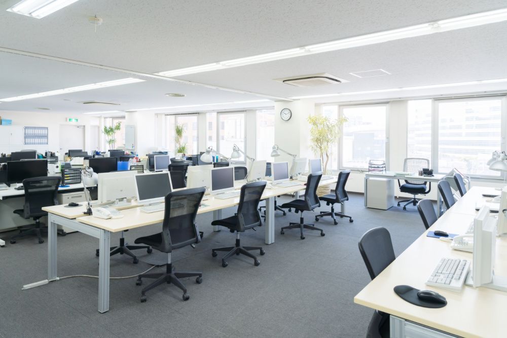 An empty office with lots of desks and chairs and computers.