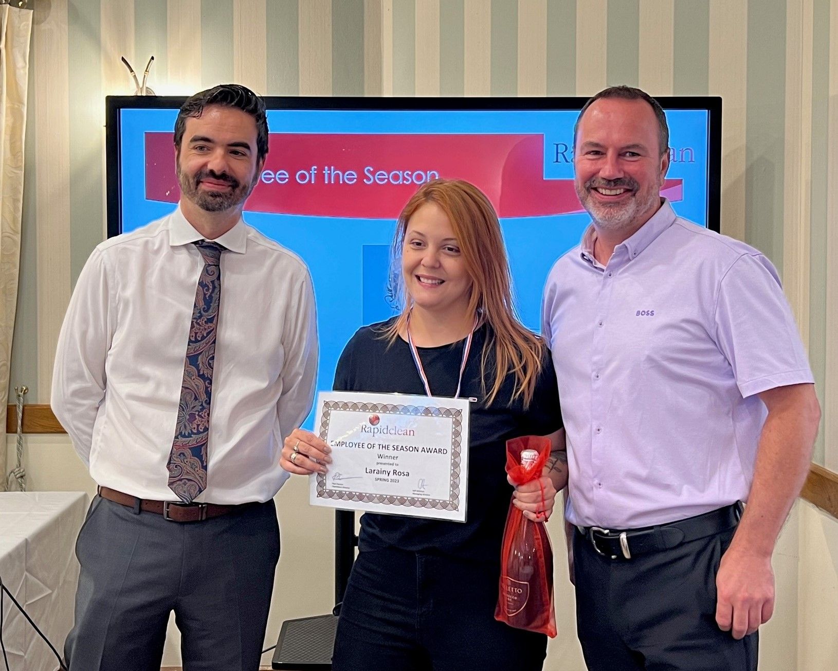 A woman is holding a certificate in front of two men