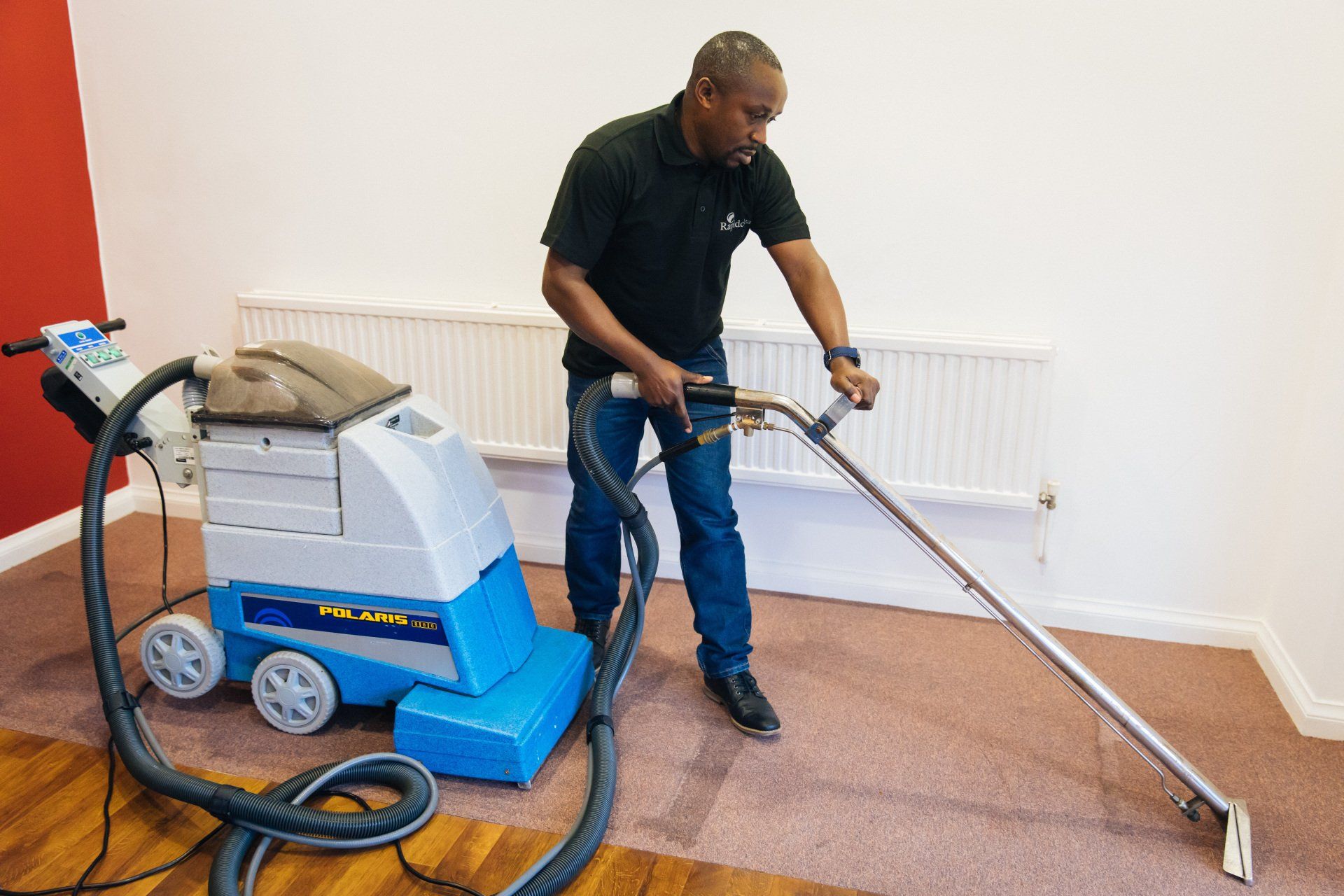 A man is cleaning a carpet with a vacuum cleaner.