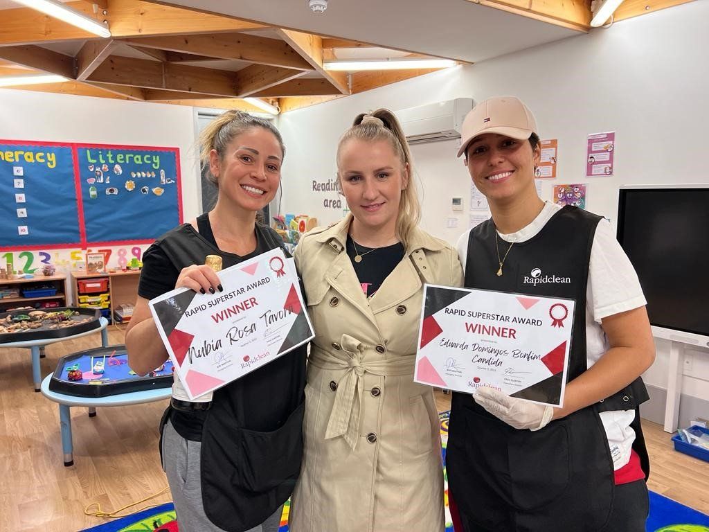 Three women are standing next to each other in a classroom holding signs.