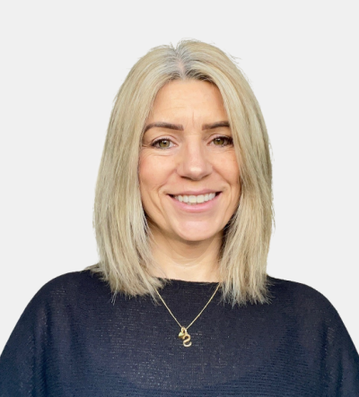 A woman wearing a black sweater and a gold necklace is smiling.