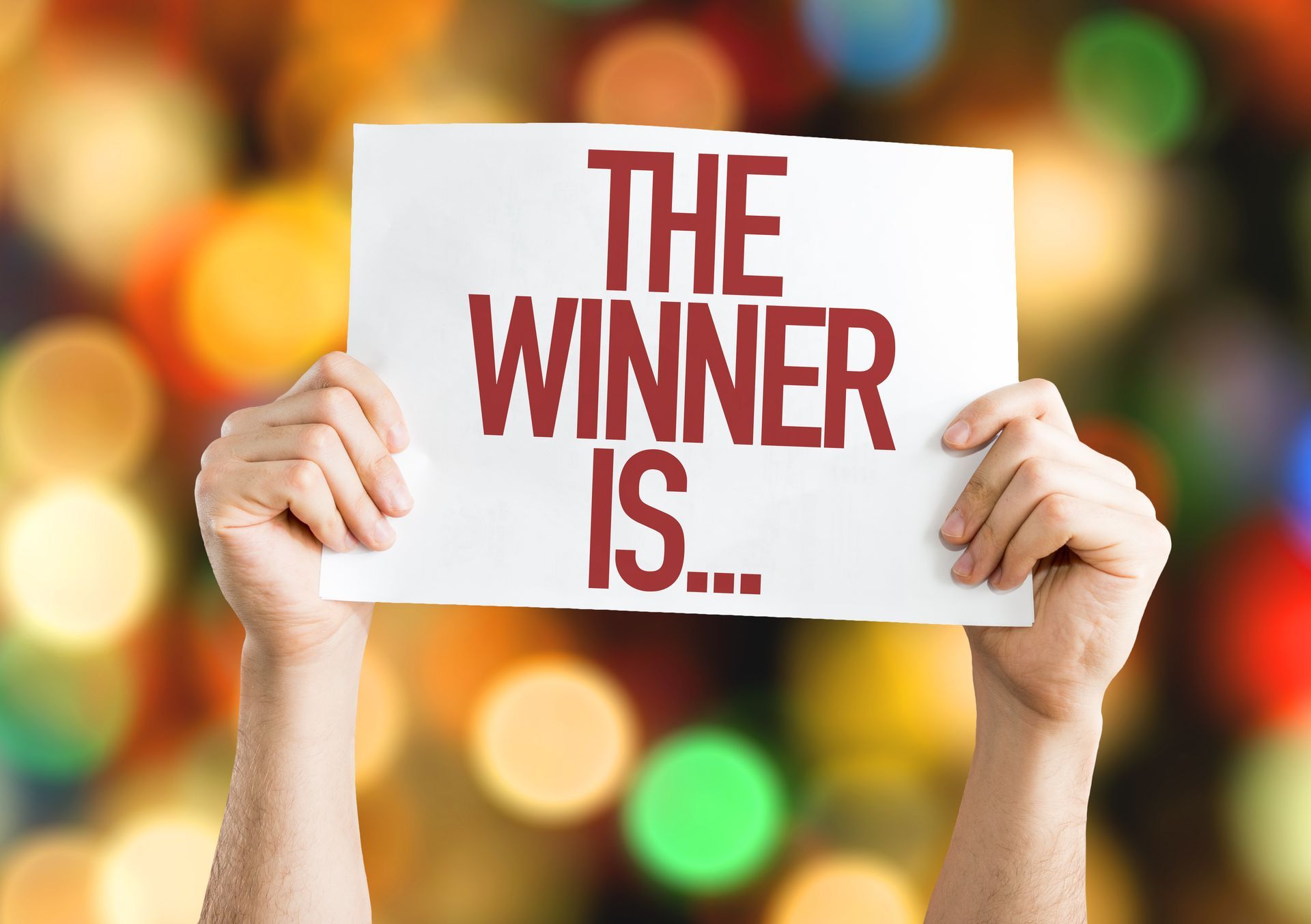 A person is holding a sign that says the winner is.