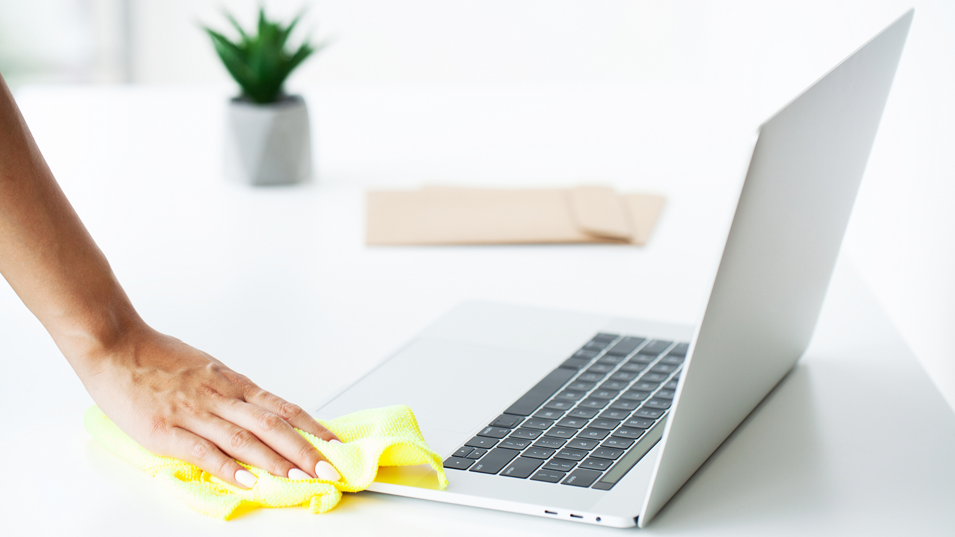 A person is cleaning a laptop computer with a cloth.