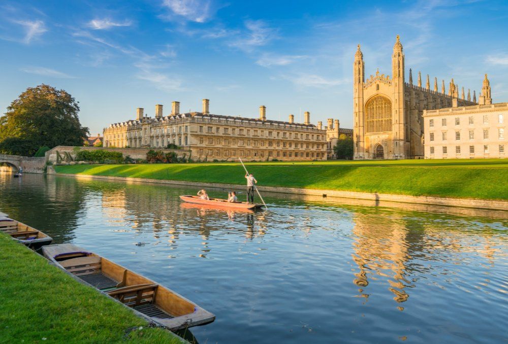 A group of people are rowing a boat down a river in front of a large building.