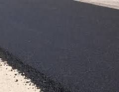 Fresh black asphalt pavement with a rough edge beside a light gravel shoulder