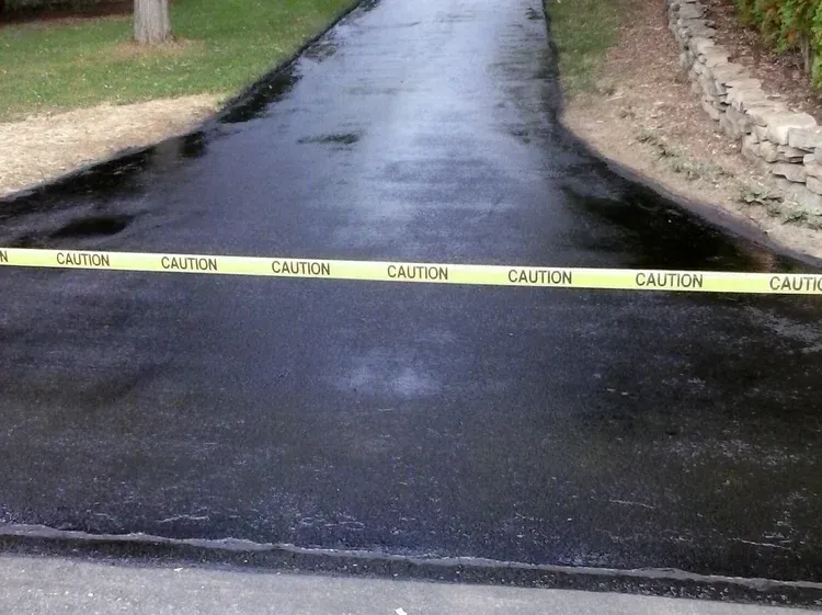 Caution tape across a wet driveway near a flooded road entrance