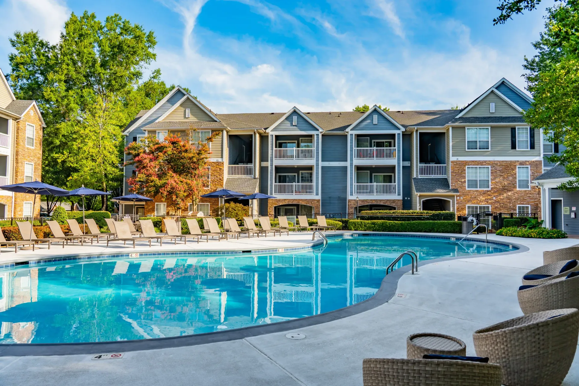 Resort-style swimming pool with lounge chairs and apartment buildings in the background.