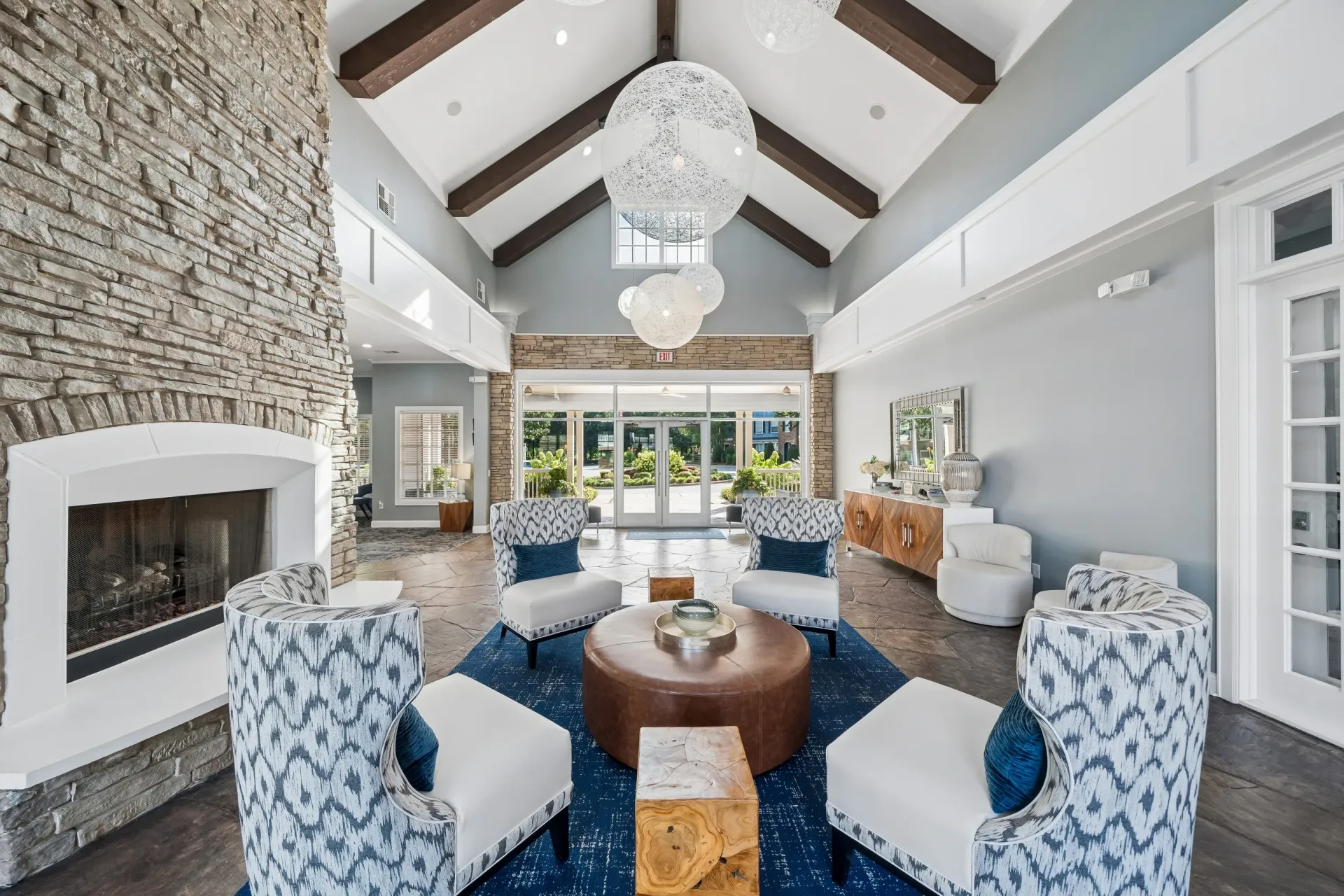 Spacious modern clubhouse lounge area with stone fireplace, comfortable seating, and large windows overlooking the grounds.