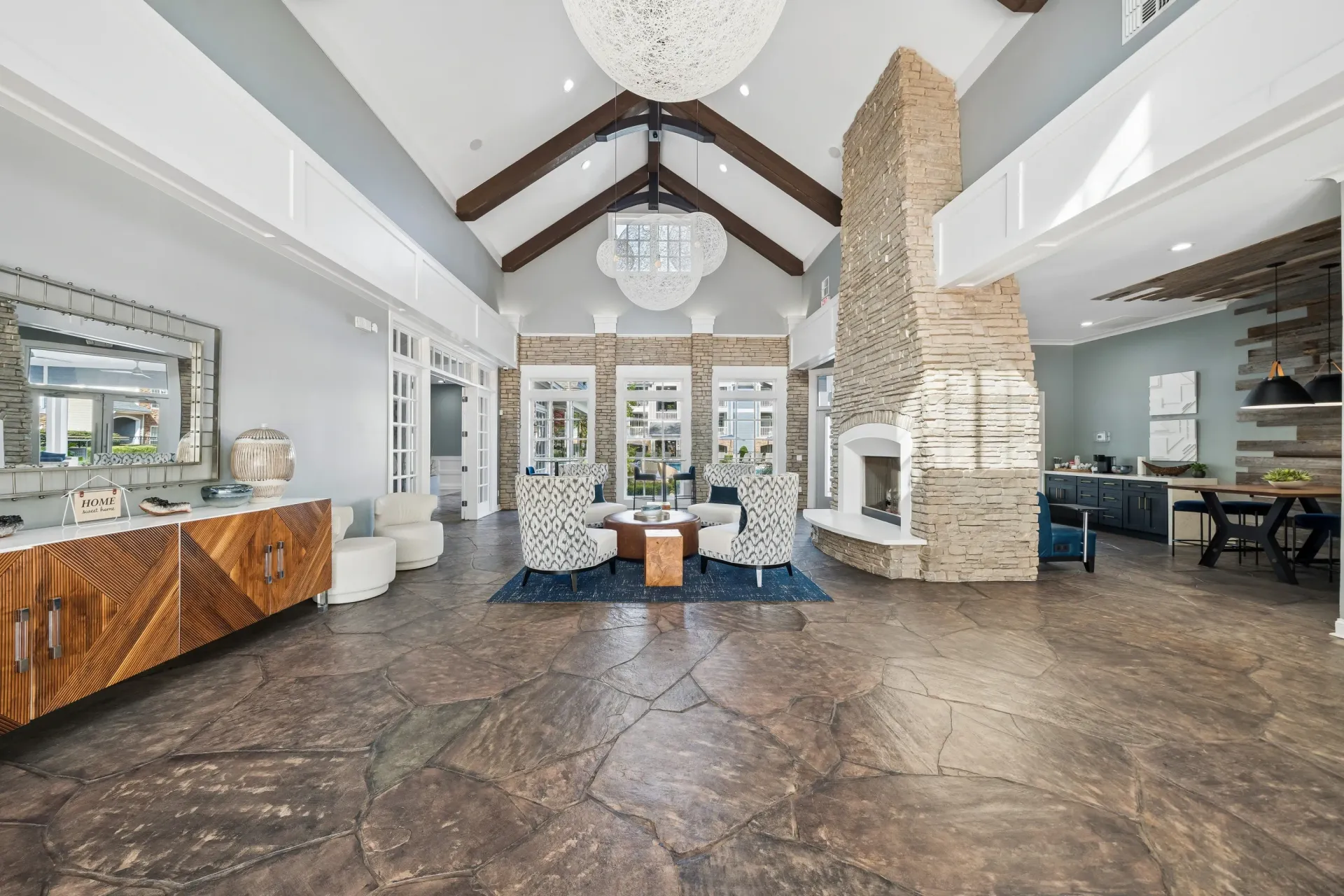 Community lounge area with a large stone fireplace, comfortable seating, and a stylish wooden cabinet.