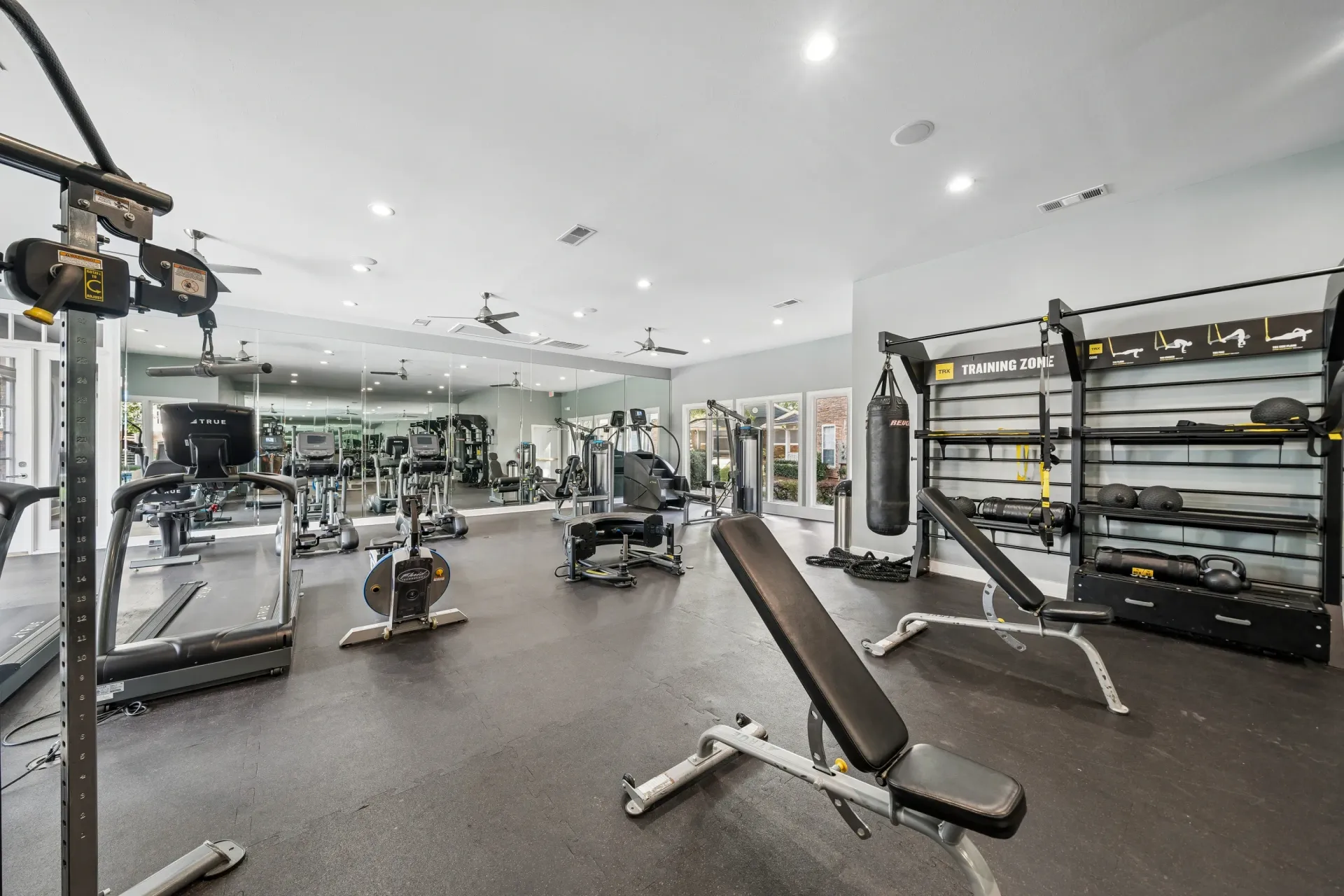 Fully equipped fitness center with cardio machines, weight machines, free weights, and a punching bag.
