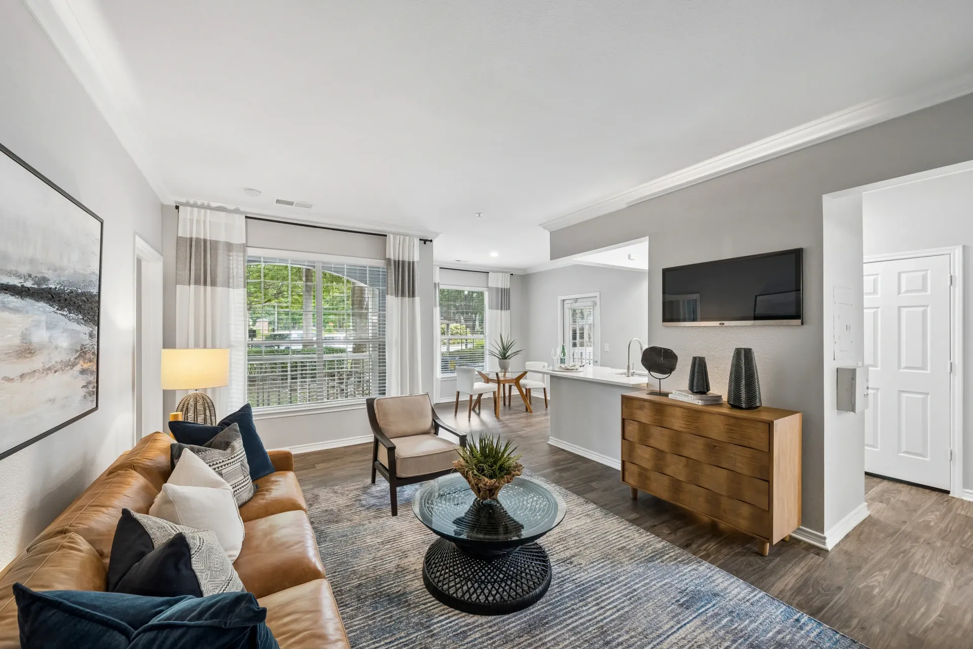 Living room with a brown leather sofa, accent chair, coffee table, and TV mounted on the wall.