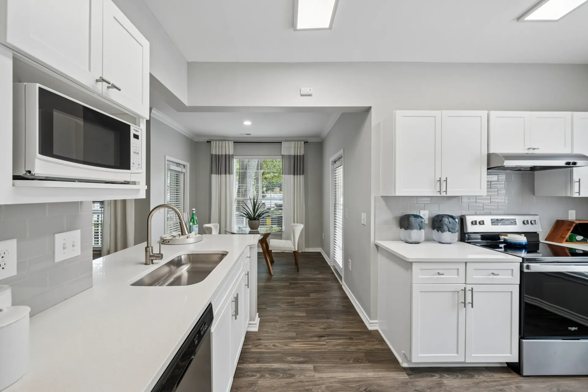 Modern kitchen with white cabinets, stainless steel appliances, and quartz countertops.