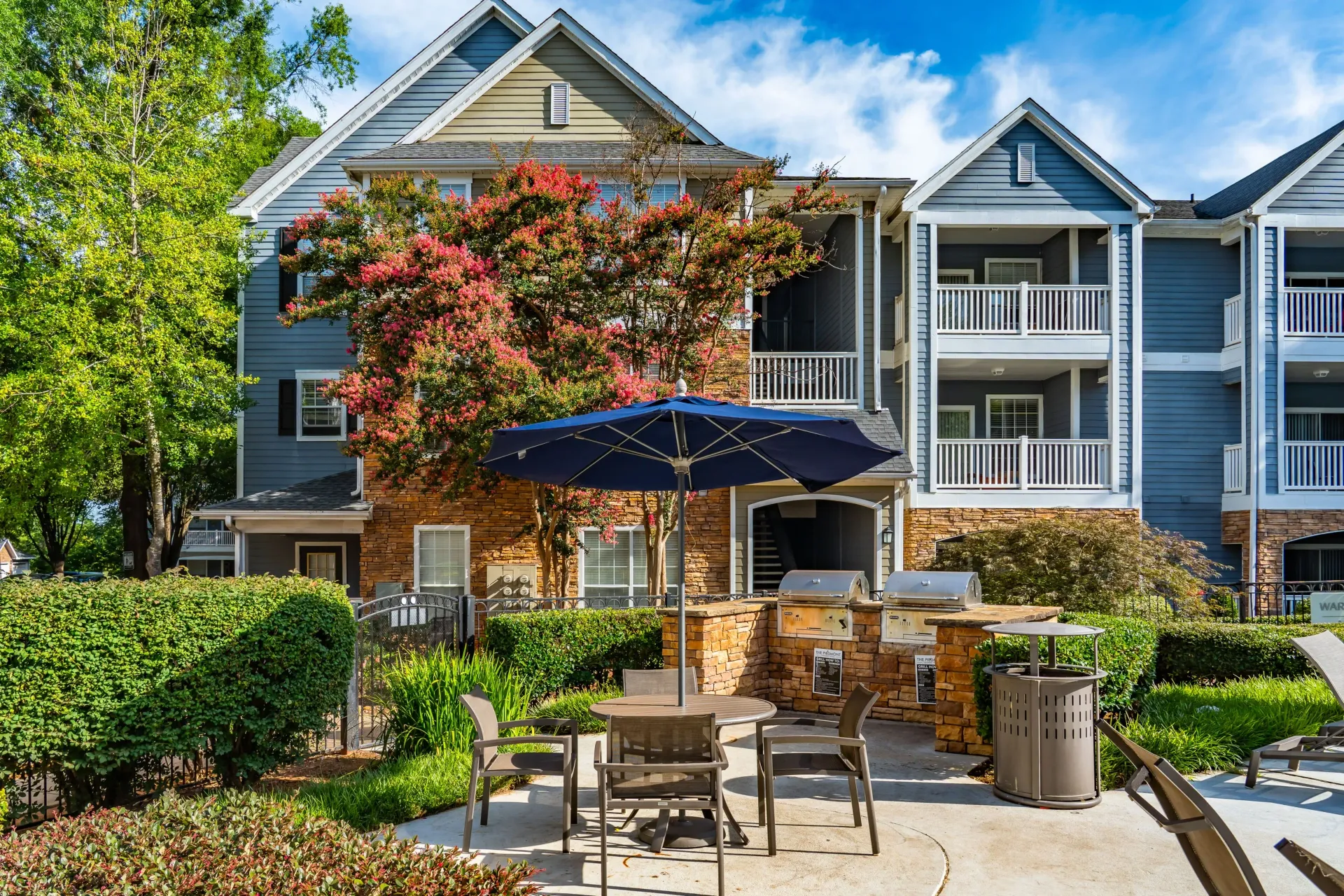 Outdoor grilling area with seating and umbrellas at a multifamily property.