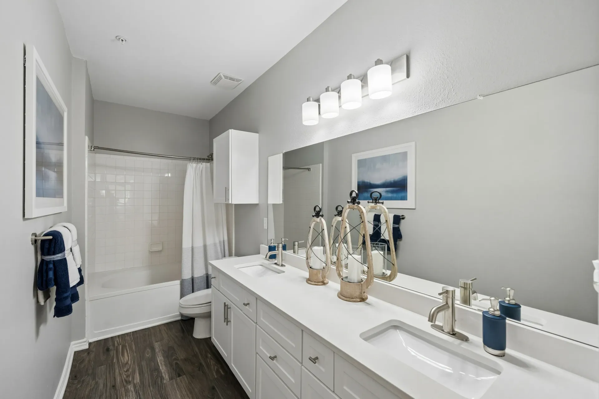 Modern bathroom with dual sinks, large mirror, and bathtub.