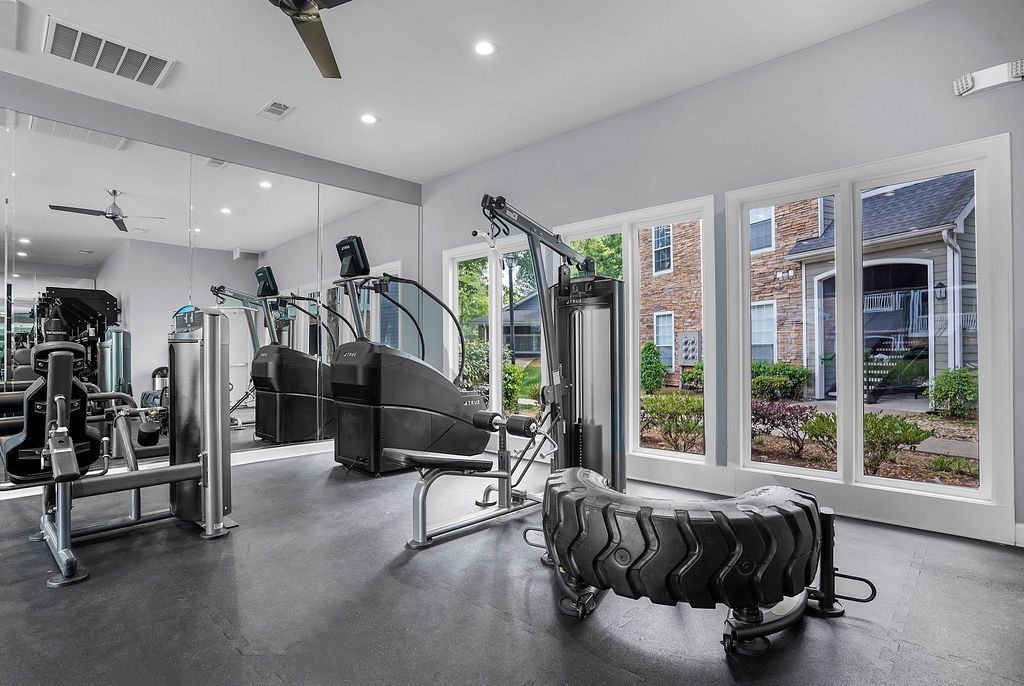 Interior of a modern apartment gym with treadmills, weight machines, and large windows at The Piedmont.