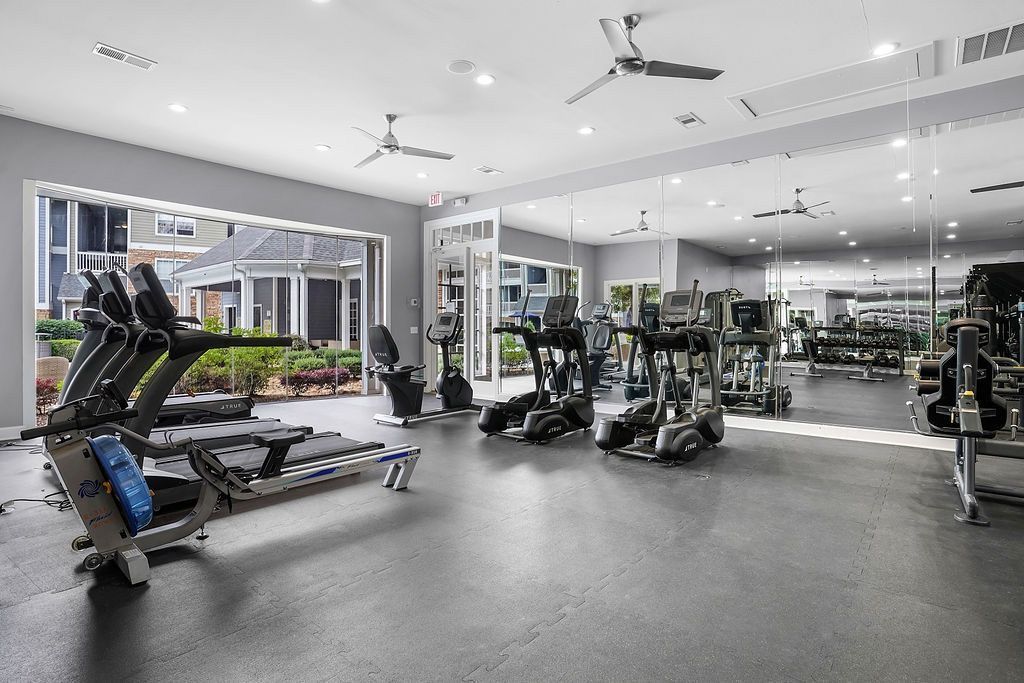 Bright indoor gym with treadmills, ellipticals, and mirrored walls at The Piedmont.