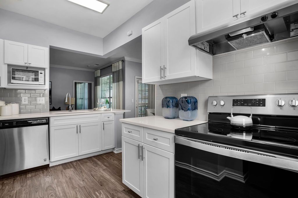Interior apartment kitchen with white cabinets, stainless steel stove, and dishwasher.