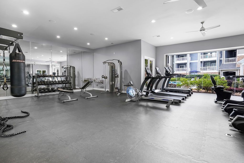 Fitness center with cardio machines, free weights, and a large mirrored wall.