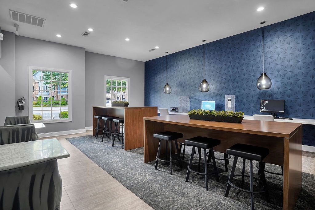 Interior community lounge with a long wooden high table, stools, and a blue patterned wallat The Piedmont.