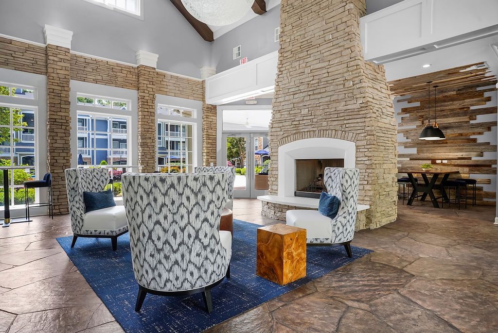 Indoor community lounge with a stone fireplace, modern chairs, and large windows at The Piedmont.