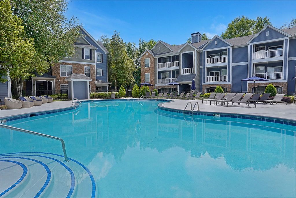 Outdoor apartment community pool with lounge chairs and surrounding buildings at The Piedmont.