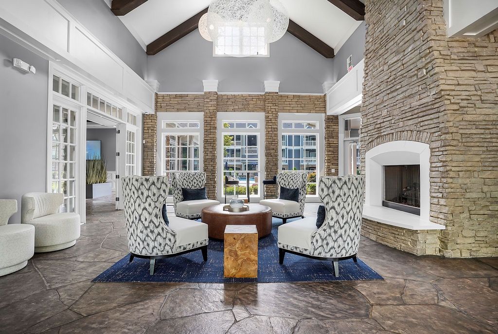 Lobby seating area with four patterned chairs around a round coffee table near a stone fireplace at The Piedmont.