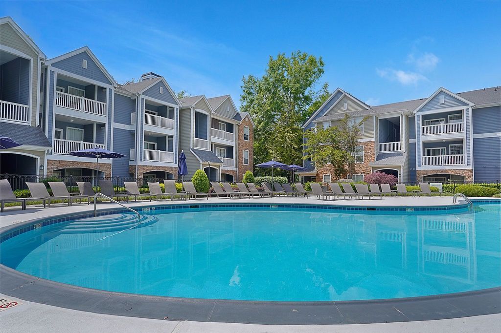 Outdoor pool area at a modern apartment community with lounge chairs and blue building facades at The Piedmont.