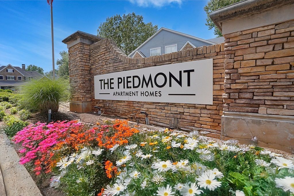 Stone brick entrance sign for The Piedmont Apartment Homes with colorful flower beds at The Piedmont.
