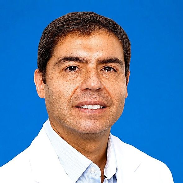 Retrato de una persona sonriente con una camisa blanca sobre un fondo azul.