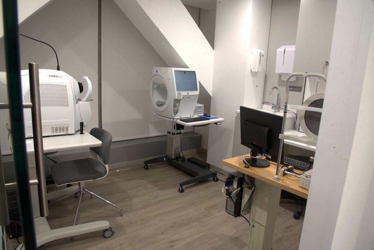 Consultorio médico pequeño con máquinas de diagnóstico, monitores y escritorios en una habitación luminosa.