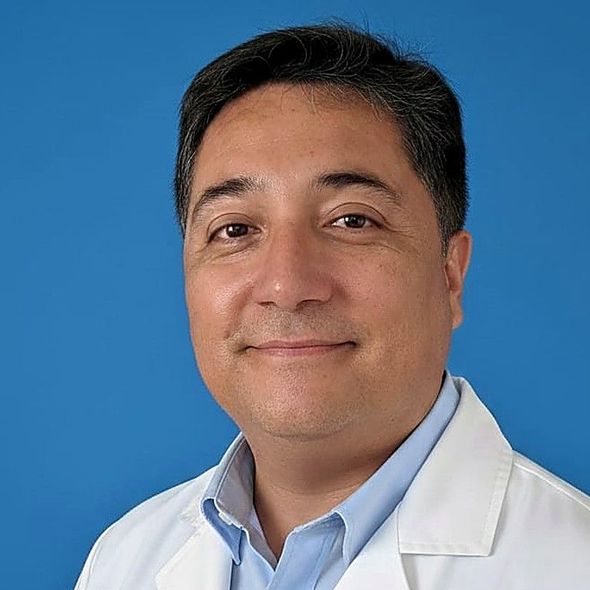Médico sonriente con bata blanca sobre fondo azul