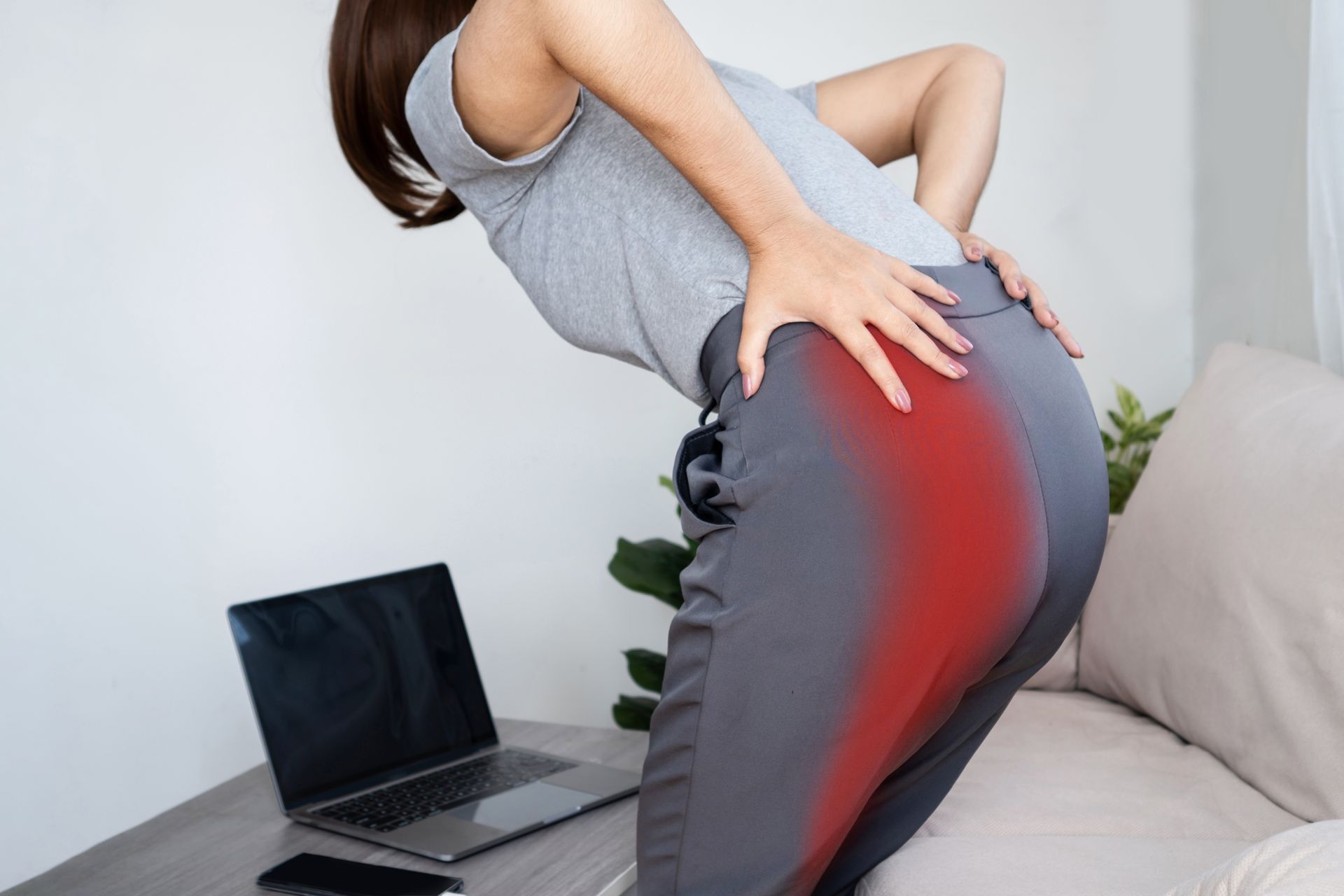 A person in grey clothing leans forward, holding their hip with a red overlay indicating pain in that area.