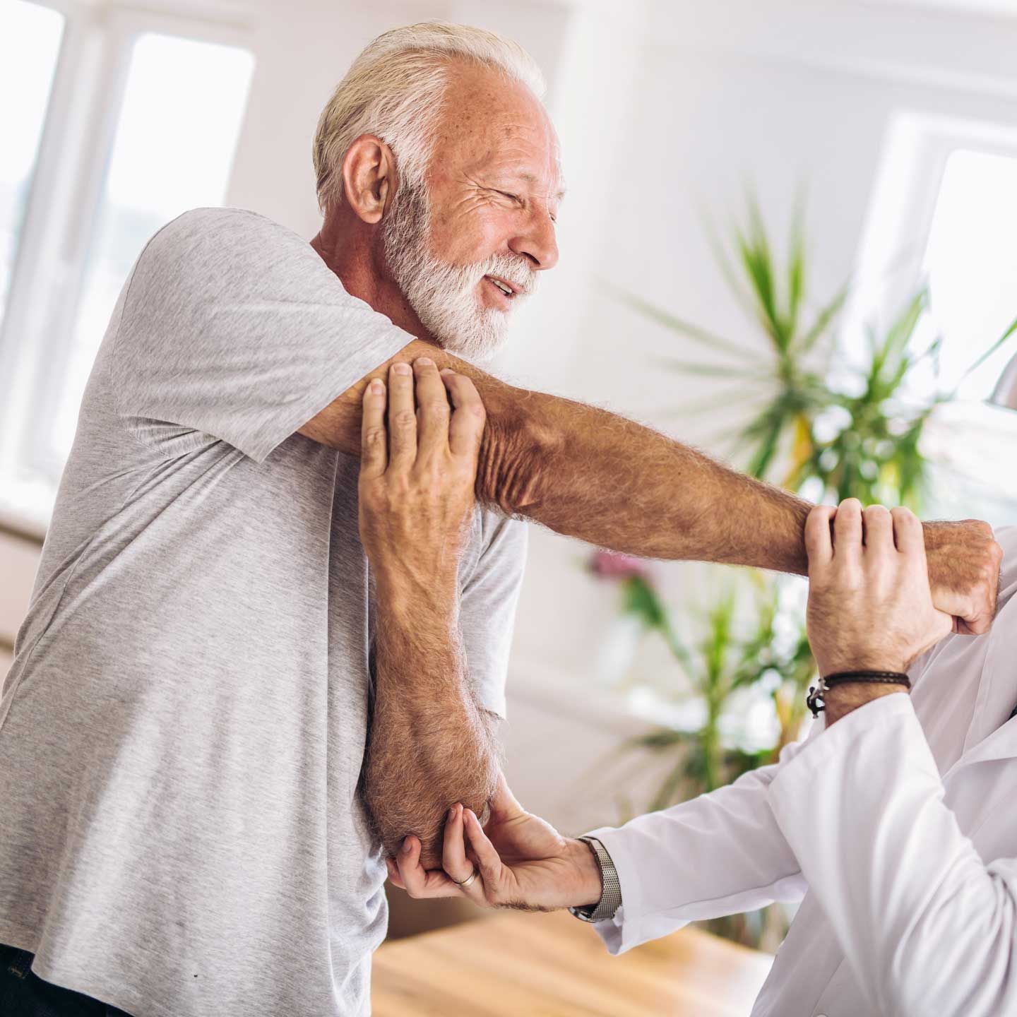 A medical professional in a white coat provides physical therapy to a patient's arm.