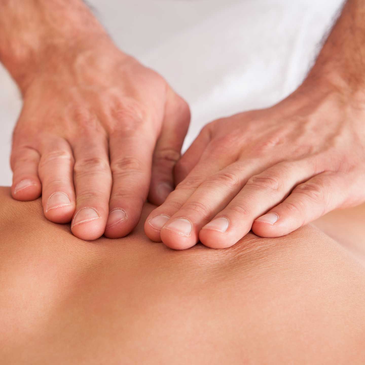Hands giving a massage to a person's back. A pair of hands performing a gentle massage on a person's upper back.