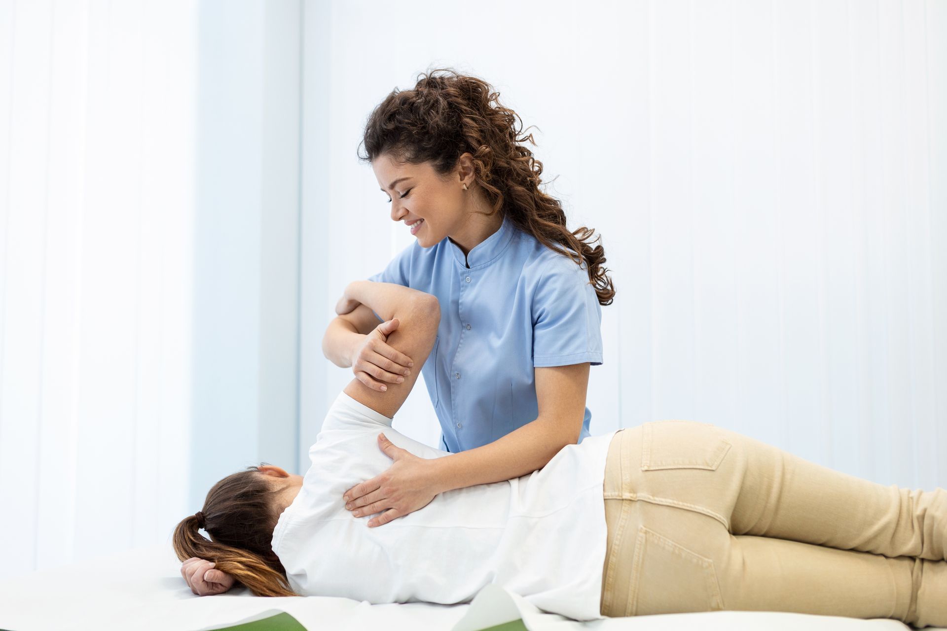 A chiropractic care provider guiding a patient through gentle shoulder mobility.