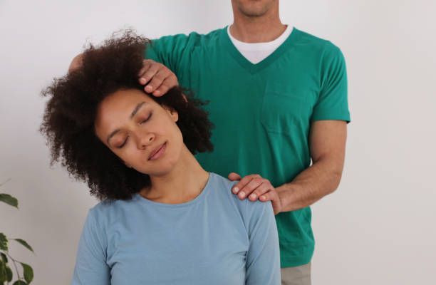 Person receiving neck massage from therapist during chiropractic or physical therapy session.