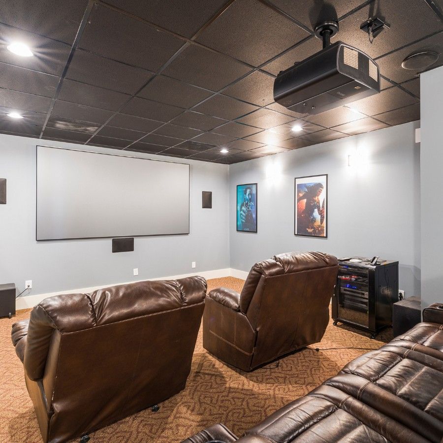 Home theater room with brown recliners, a large projection screen, and movie posters on white walls
