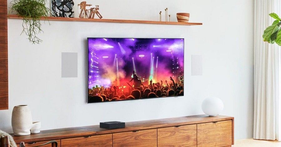 Wall-mounted TV showing a colorful concert scene above a wooden console in a bright living room