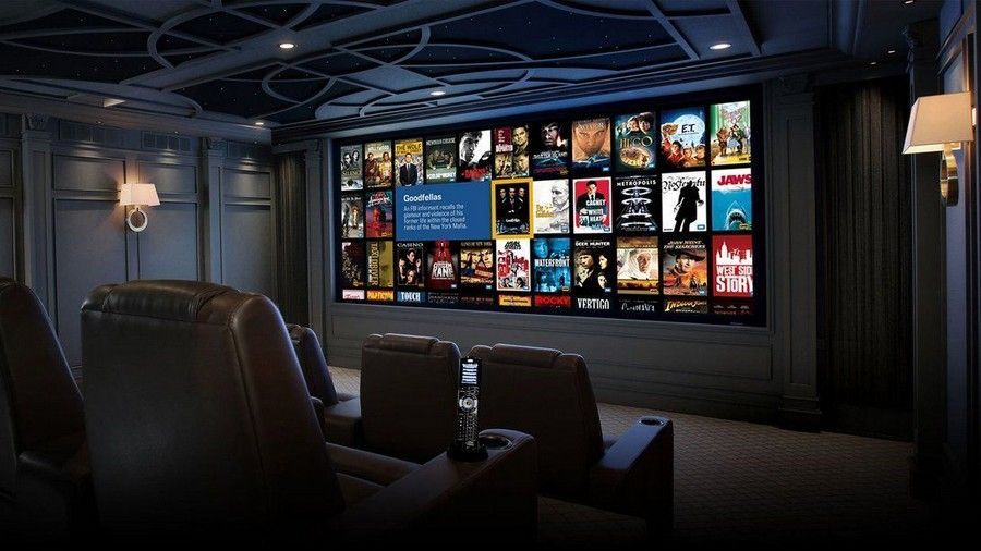 Dark home theater with recliners facing a wall of colorful movie posters on a large screen